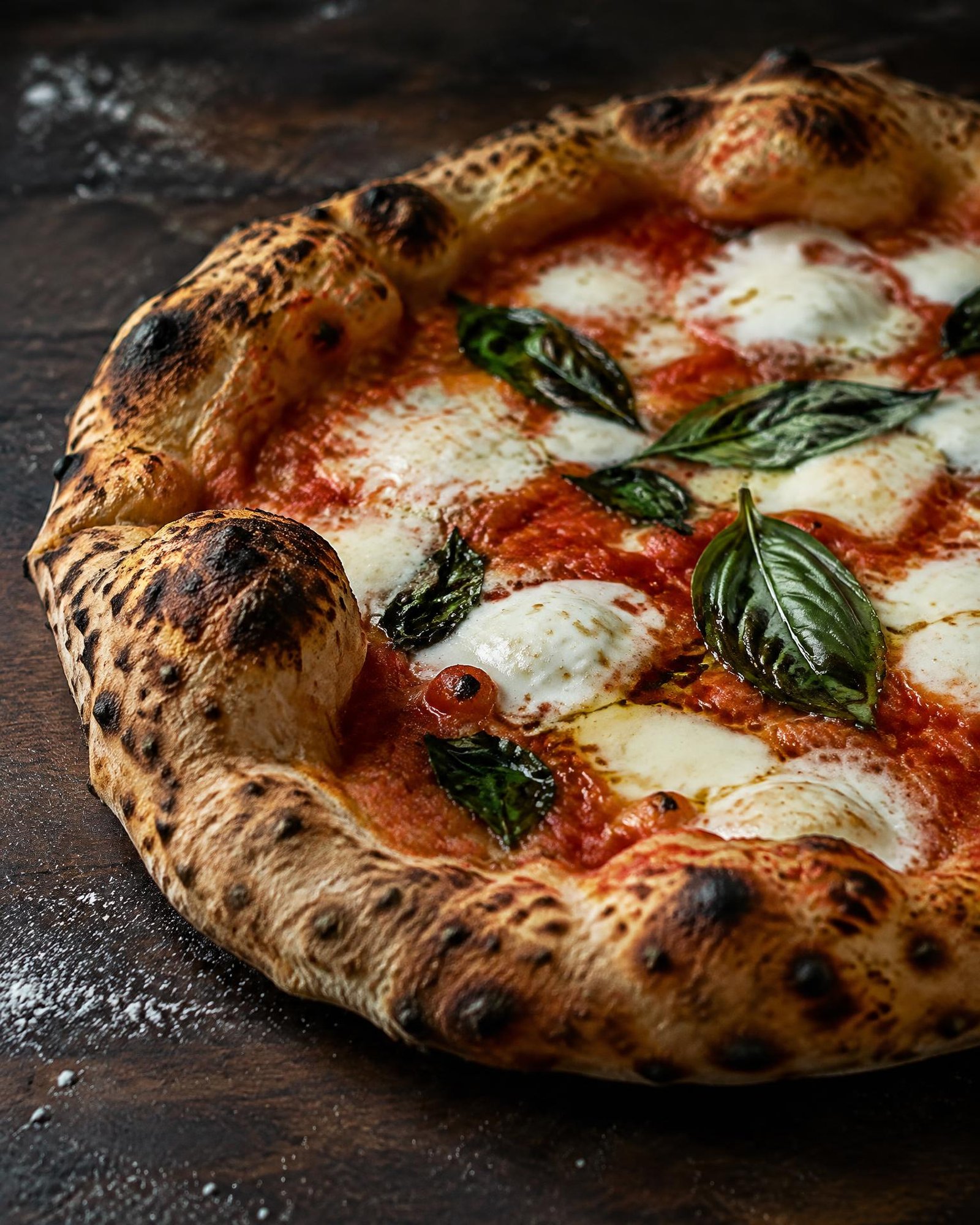 Pizza mit luftigem, geflecktem Teigrand, Büffelmozzarella und Basilikum
