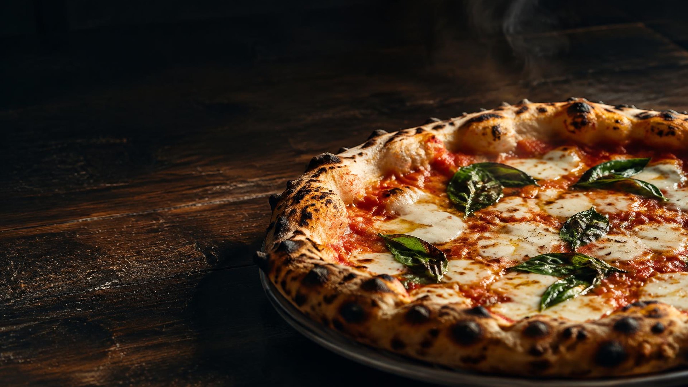 Neapolitanische Pizza Margherita frisch aus dem Holzofen auf dunklem Holztisch